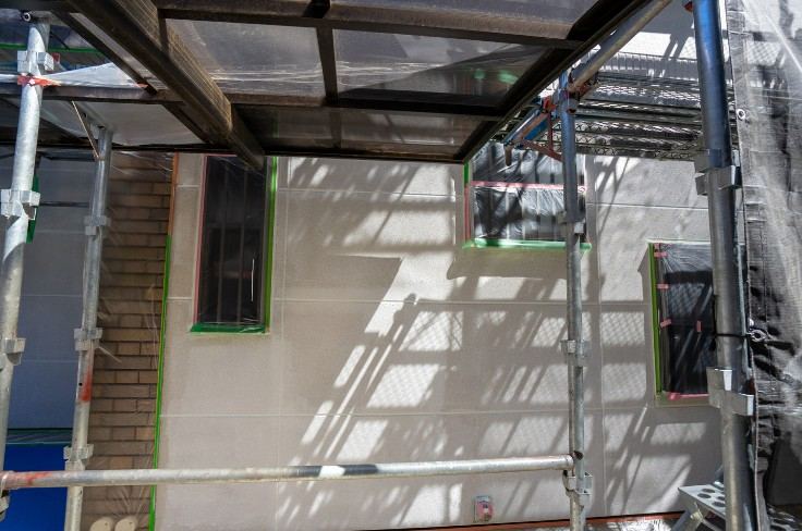 Andamio con marquesina de protección y lona sobre una fachada con las ventanas enmascaradas: marquesina de protección en obra