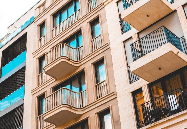 Balcones y voladizos de edificios de viviendas en Mallorca Balcones curvos y revestimiento pétreo en la fachada de un edificio de viviendas: fachada rehabilitada con acabado en piedra