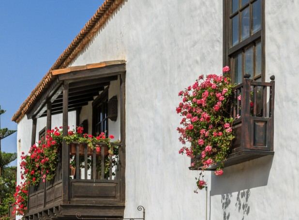 Casa tradicional con balcón de madera, geranios y fachada encalada: fachada encalada tradicional