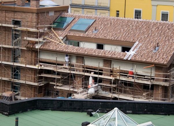 Cubierta de teja y andamios en la rehabilitación de un edificio de ladrillo: reparación de cubierta con teja