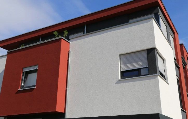 Edificio moderno con revestimiento gris, paños rojos y persianas: acabado de fachada en dos tonos