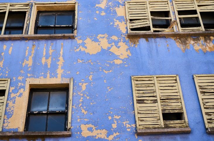 Repintado de fachadas deterioradas en Mallorca Fachada azul con la pintura desconchada y contraventanas deterioradas: pintura desconchada en fachadas