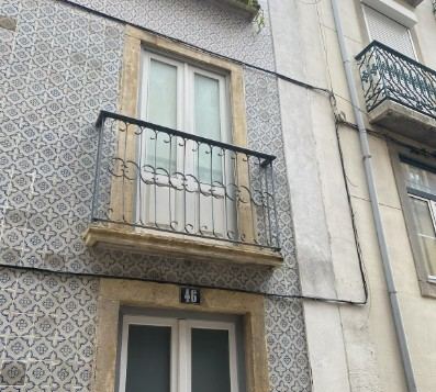 Fachada de azulejos con balcón de forja y bajante en un edificio antiguo: conservación de fachadas con azulejo