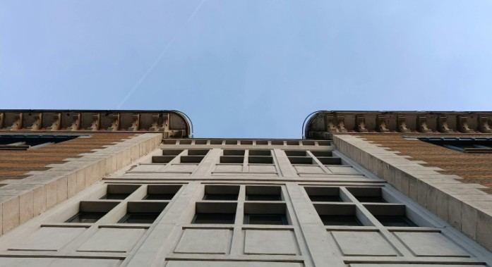 Conservación de fachadas de piedra en Mallorca Fachada de un edificio histórico vista desde abajo, con cornisa y huecos de ventana: ITE de edificios antiguos