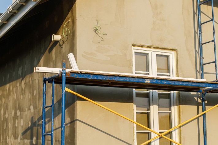 Fachada con aislamiento exterior en Mallorca Fachada de vivienda con las placas de aislamiento colocadas en parte y andamio azul: obra de aislamiento por fases
