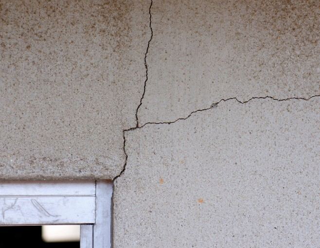 Fisuras en forma de T en el revoco, sobre el marco de una ventana: reparación de fisuras en fachada