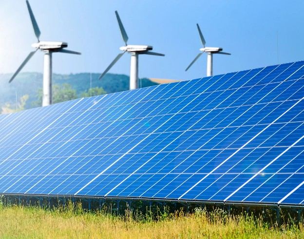 Campo de paneles solares con aerogeneradores al fondo: energías renovables en edificios